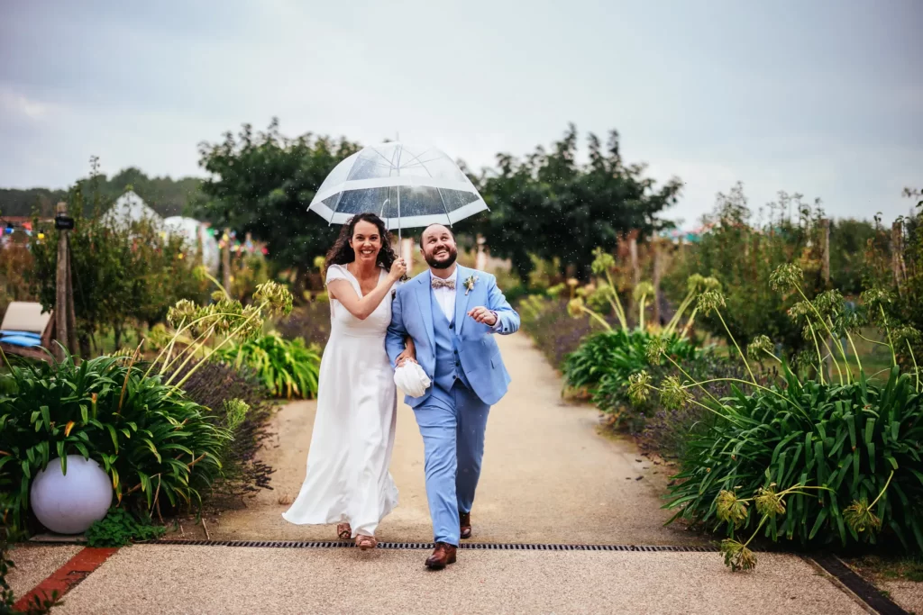 Photo de mariés heureux sous la pluie avec un parapluie