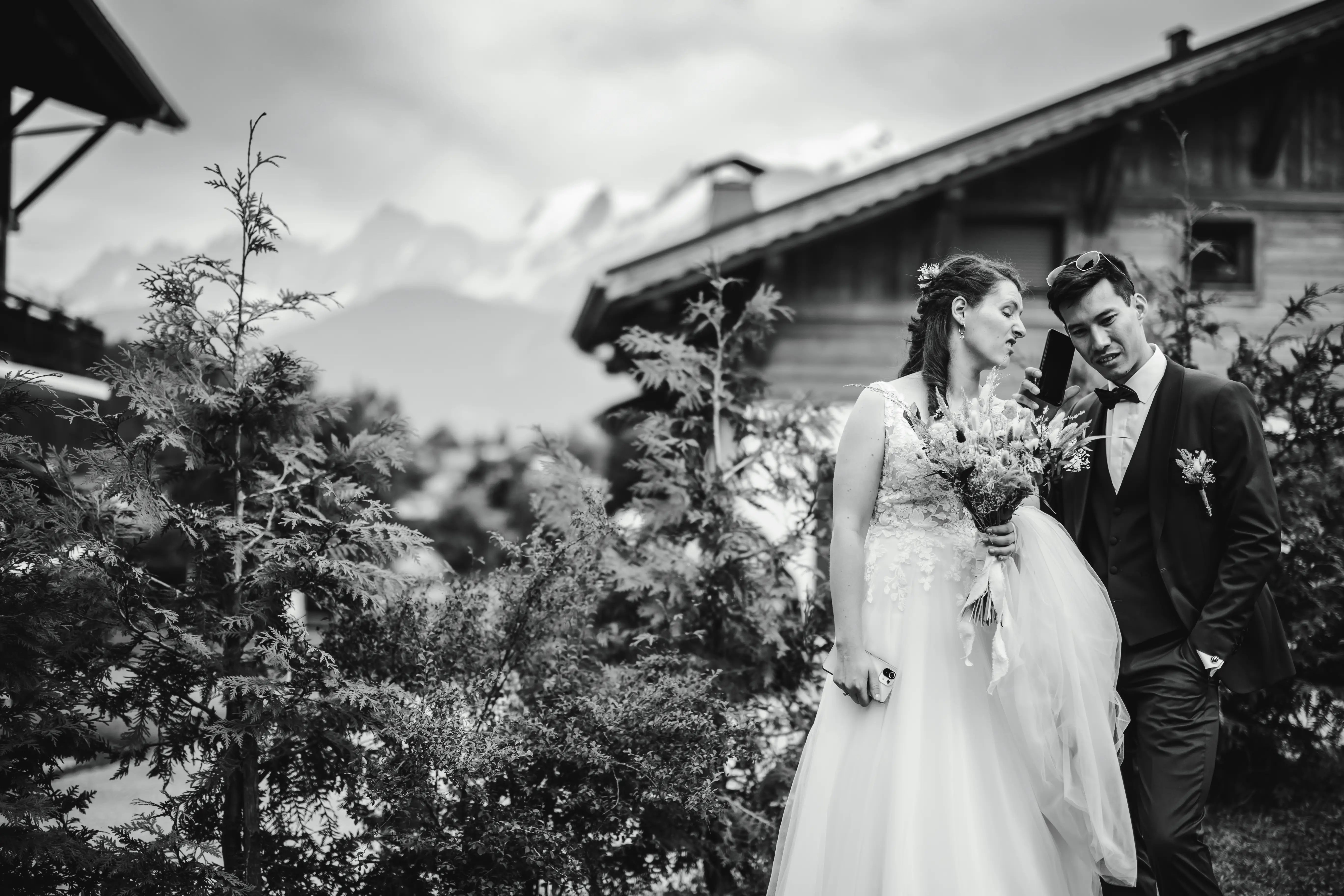Mariés au téléphone avec montagne du Mont-Blanc et chalet en fond